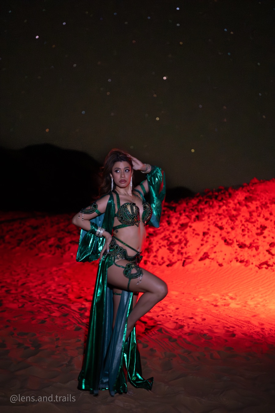 Dancer in green lit by red desert light at night