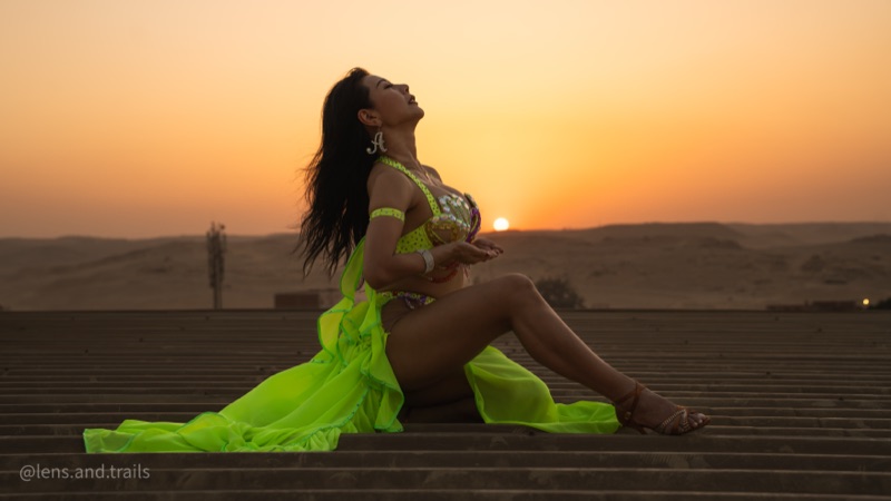 Dancer in flowing green fabric at sunset on the desert dunes