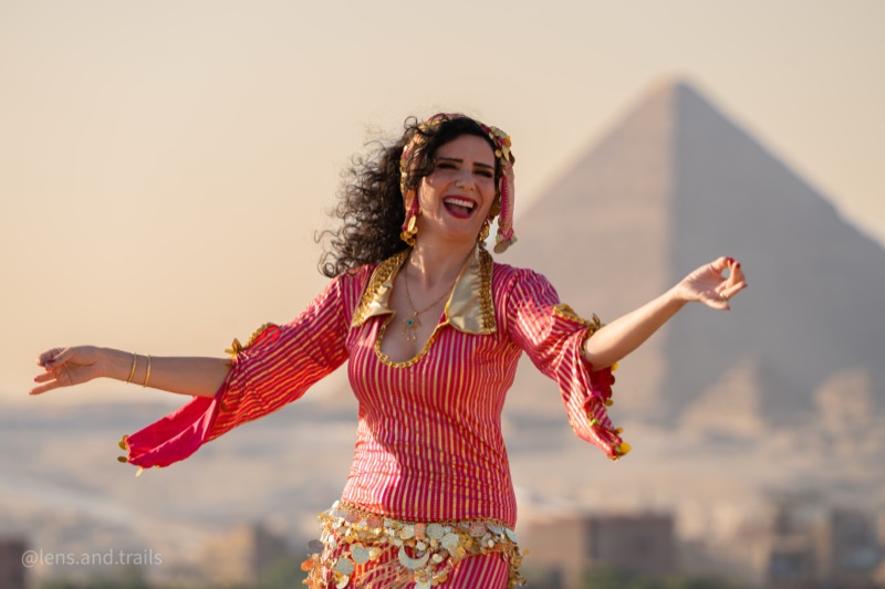 Oriental dancer in red and gold costume in front of the Giza pyramids